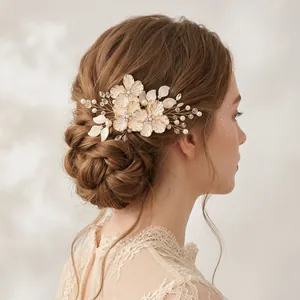 Dettaglio dell'accessorio sposa con fiori dorati e perle in un'acconciatura raccolta
