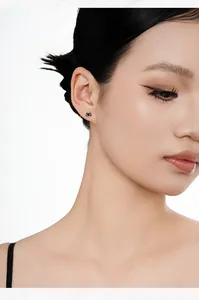 Detailed close-up showing a tiny black cat silver stud earring on female model ear