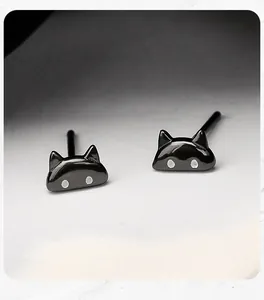 Close-up detail of minimalist glossy black cat-shaped sterling silver stud earrings