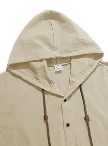 Close-up detail of a beige hooded cotton shirt showing fabric texture and size tag.