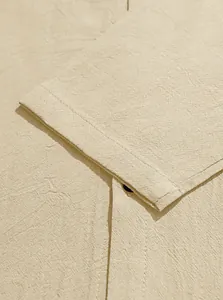 Macro view of the breathable cotton linen fabric and stitching on a beige casual shirt.