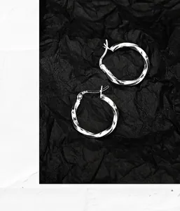 Detailed view of S925 sterling silver Mobius twist hoop earrings on black background