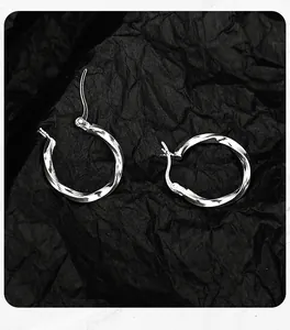 Close-up detail of S925 sterling silver Mobius twisted hoop earrings on black paper