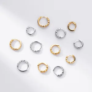 Close-up of elegant silver and gold huggie hoop earrings with sparkling cubic zirconia