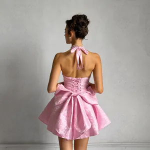 Detailed back view of a pink jacquard halter dress featuring a large bow and corset lacing.