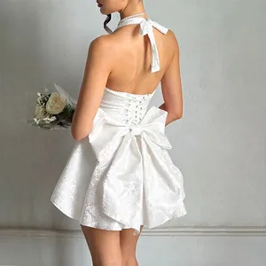 Detailed back view of white jacquard halter dress with a large bow and lace-up design