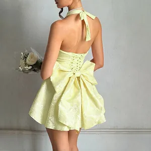 Detailed back view of a yellow jacquard halter dress with a large bow and lace-up back