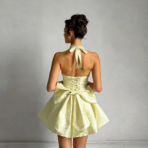 Detailed back view of elegant yellow jacquard halter mini dress with large bow.