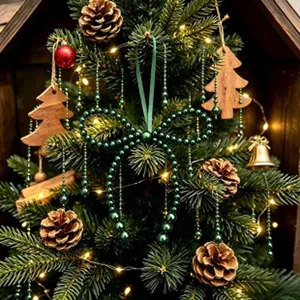 Dettaglio di un addobbo natalizio a fiocco di perline verde scuro con luci festive