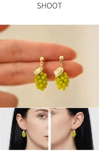 Detailed view of sweet green grape dangle earrings with gold leaf and wearing effect
