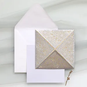Detailed view of a silver glitter laser-cut wedding invitation with a white envelope set