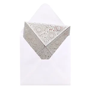 Detail of silver glitter laser-cut wedding invitation with elegant lace pattern and envelope