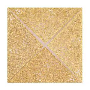 Close-up of laser-cut gold glitter wedding invitation card with intricate lace details.