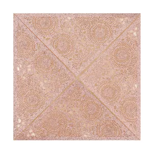 Macro detail of laser-cut rose gold glitter wedding invitation with lace floral pattern