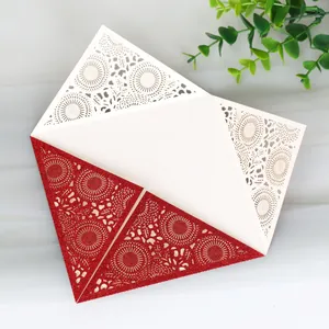 Detail of red glitter laser cut wedding invitation card with lace floral patterns.