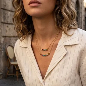 Detail of layered gold necklaces with colorful rainbow gemstones on a model