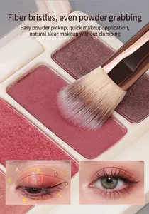 Close-up of soft synthetic eye blending brush picking up pink eyeshadow powder from palette