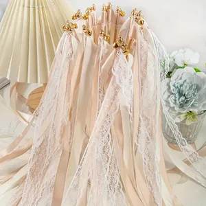 Vue détaillée de baguettes en ruban de mariage champagne et dentelle avec clochettes d'or