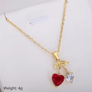 Elegant gold cherry pendant necklace featuring red and clear heart-shaped crystals