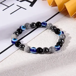 Detailansicht eines Armbands mit bösem Blick sowie schwarzen, grauen und metallischen Perlen.