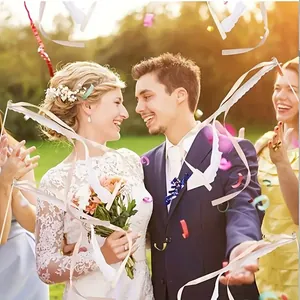 Scène de mariage joyeuse en plein air avec des rubans blancs volant autour du couple.