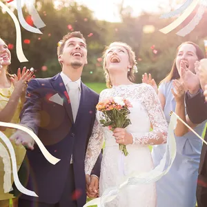 Invités de mariage célébrant avec des baguettes de ruban blanc et argenté à cloches