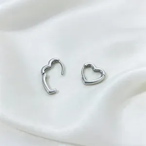 Detailed close-up view of silver heart-shaped hoop earrings on elegant white silk