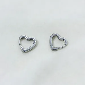 Detailed view of silver-toned hollow heart-shaped hoop earrings on white fabric