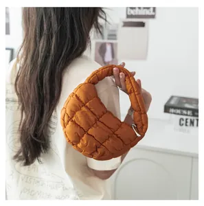 Dettaglio di una mini borsa a mano trapuntata arancione tenuta da una modella in posa.