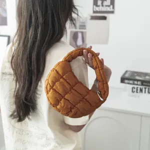 Borsa a mano trapuntata a nuvola marrone alla moda tenuta da una modella per un look chic urbano