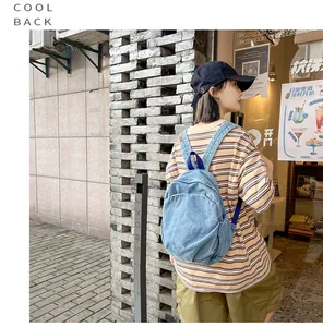 Una mujer joven con una mochila de mezclilla lavada vintage en un entorno urbano moderno.