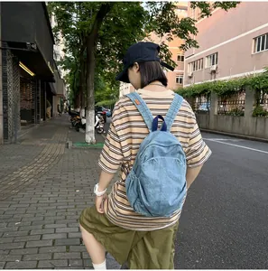 Vista trasera de una modelo con una mochila de mezclilla lavada azul vintage urbana