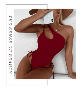 Detail view of a sexy one-shoulder one-piece swimsuit in dark red color for women