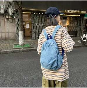 Mochila de mezclilla azul lavada retro usada por una modelo en un entorno de calle urbana