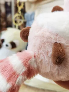 Makro-Detail der weichen rosa-weißen Fellstruktur eines süßen Waschbär-Plüsch-Schlüsselanhängers
