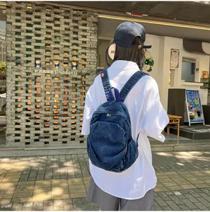 Vista trasera de una mujer con una mochila de mezclilla lavada en un entorno urbano real