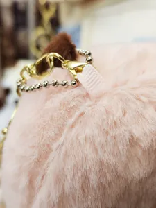 Nahaufnahme der weichen rosa Plüschtextur und hochwertigen goldenen Metall-Schlüsselanhänger