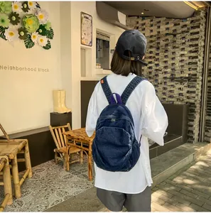 Vista trasera de una mochila de mezclilla azul oscuro usada con un atuendo urbano casual
