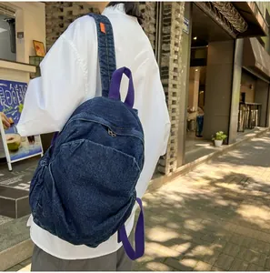 Vista lateral de mochila vintage de mezclilla lavada con correas moradas en la calle