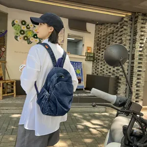 Mujer con mochila de mezclilla lavada vintage en un entorno urbano al aire libre