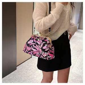 Elegant black evening bag with pink sequins shown on model in a modern indoor environment