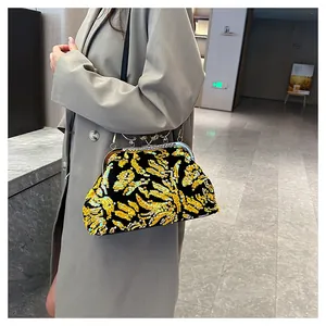 Detailed view of an elegant gold sequined evening clutch bag worn with a gray coat.