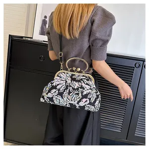 Detail view of luxurious evening handbag with floral sequins and vintage metal handle.