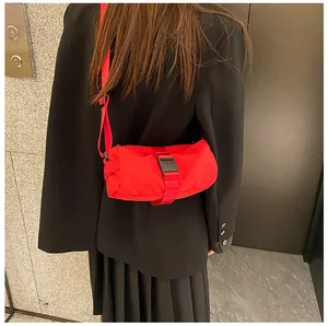Vista detallada de un bolso bandolera cilíndrico rojo de tela Oxford con hebilla negra