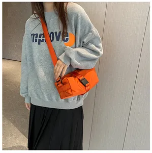 Vista detallada de bandolera de tela Oxford naranja vibrante combinada con sudadera gris