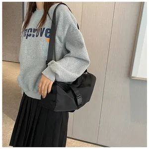 Detalle de un bolso bandolera grande negro de tela Oxford para viajes de mujeres.