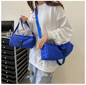 Bolso bandolera grande azul de tela Oxford usado por una modelo en un entorno real