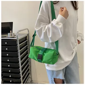 Modelo con un bolso bandolera cilíndrico de tela Oxford verde brillante con hebilla