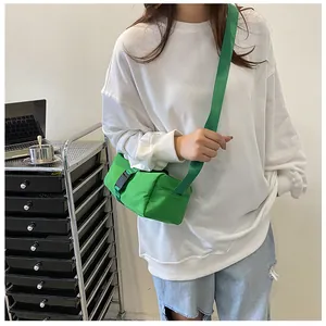 Bolso bandolera de tela Oxford verde vibrante usado por una modelo en ambiente.