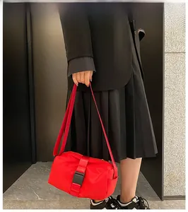 Detalle de un bolso bandolera rojo de tela Oxford con hebilla negra de gran capacidad.
